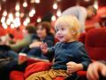 Cute toddler boy watching cartoon movie in the cinema