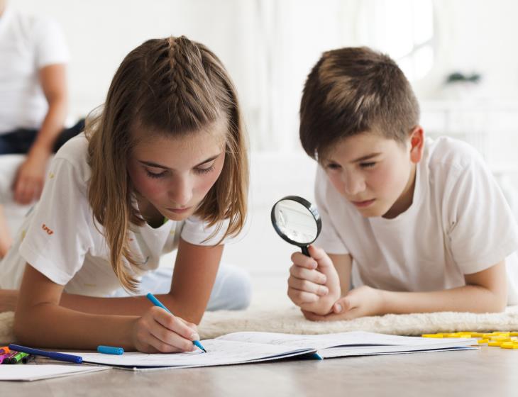 boy-looking-through-magnifying-glass-his-sister-drawing-book