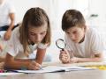 boy-looking-through-magnifying-glass-his-sister-drawing-book