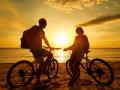 Couple tourists with Bicycles Watching Sunset. Silhouette people